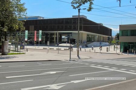 Im unteren Bildteil verläuft die Nonntaler Hauptstraße, die mit Pfeil rechts abbiegen ihren Verlauf ändert. Geradeaus rechts verläuft die Petersbrunnstraße. Im oberen Bildteil Mitte das Gebäude Unipark Nonntal, links davor verläuft die Josef-Preis-Allee und rechts, wo man Radfahrer ist, ist der nördliche Beginn der Erzabt-Klotz-Straße, der nur für Radfahrer und Fußgänger benutzbar ist.