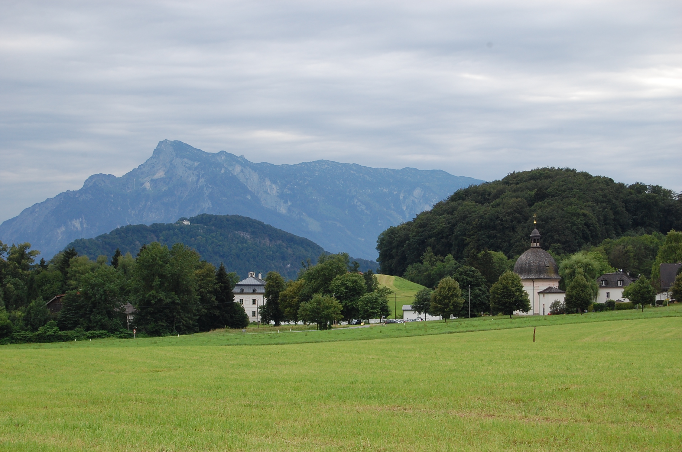 Söllheim, Kirche u. Schloss mit Kapuzinerberg u. Untersberg im Hintergrund